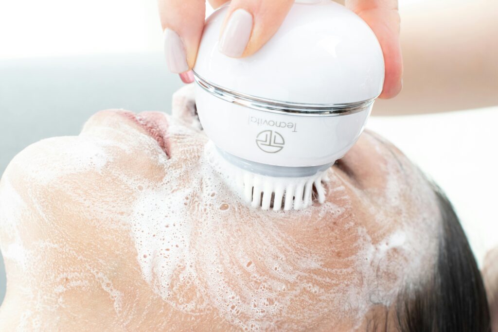 Woman's face being cleaned with an electric cleansing brush and foam.